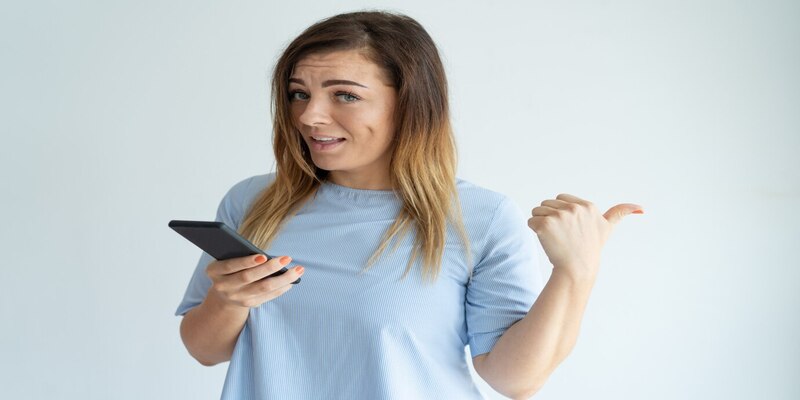 mujer sonriente que senala lado pulgar que sostiene smartphone 1262 14422