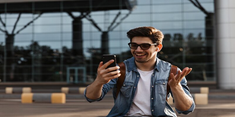 hombre moreno feliz gafas sol chaqueta mezclilla sonrie sostiene telefono 197531 27101